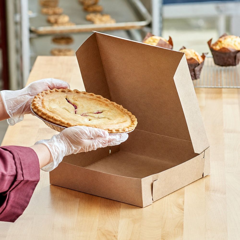 A freshly baked pie being boxed for takeaway
